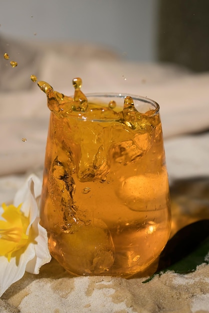 Glas mit Orangengetränk am Sandstrand