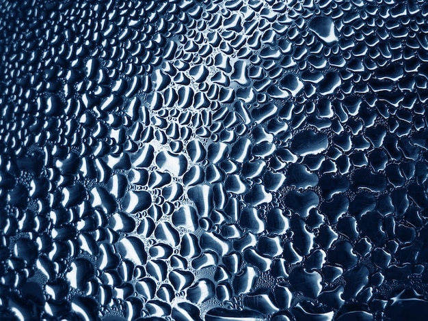 Glas mit Regentropfen auf blauem Hintergrund