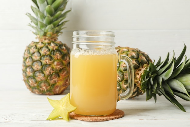 Glas mit Saft und Ananas auf weißem Holzhintergrund, Platz für Text