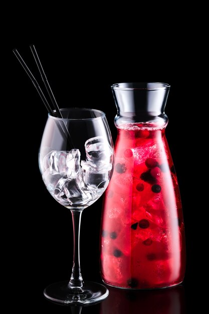 Glas mit Sangria mit Waldbeeren und einem Weinglas lokalisiert auf schwarzem Hintergrund