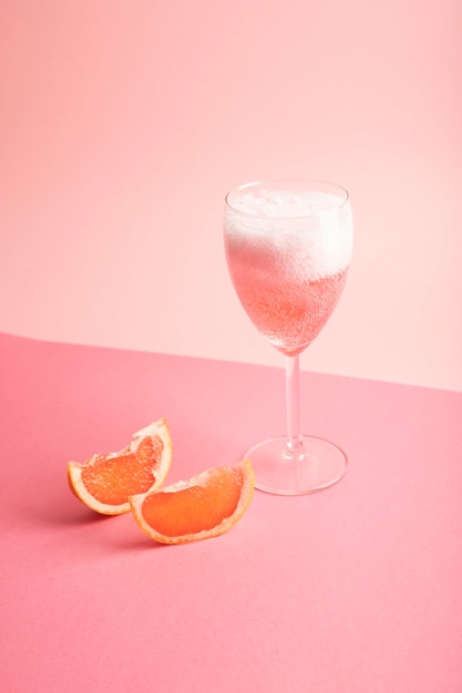 Glas mit Sekt und Grapefruit auf Rosa