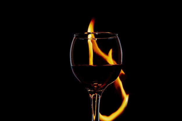 Glas mit Wein auf Feuer und Flamme auf einer schwarzen Hintergrundisolierung