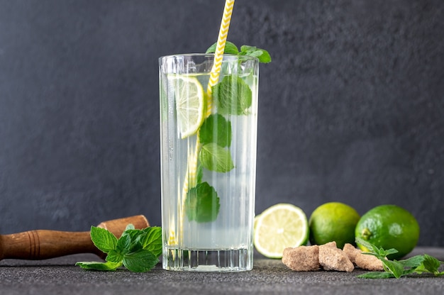 Glas Mojito-Cocktail mit Zutaten an der dunklen Wand