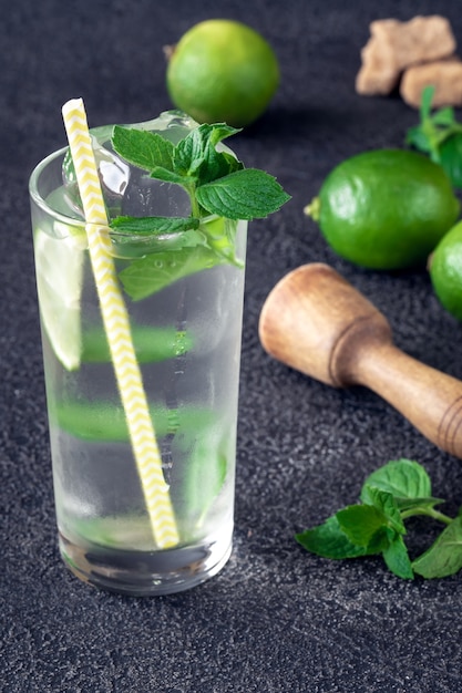 Glas Mojito-Cocktail mit Zutaten auf dunkler Oberfläche