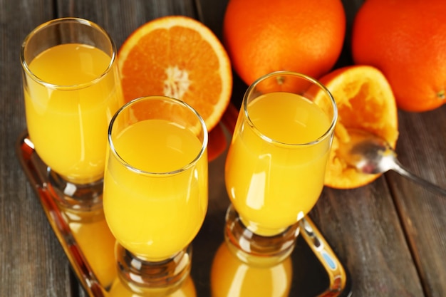 Glas Orangensaft mit Scheiben auf Metalltablett auf rustikalem Holzhintergrund