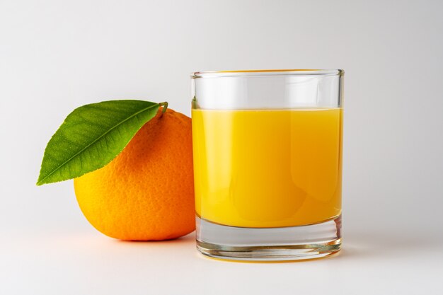 Glas Orangensaft und Orangenfrucht auf weißem Hintergrund.