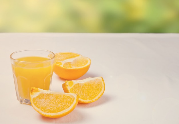 Glas Orangensaft und Scheiben der orange Frucht auf weißer Tabelle