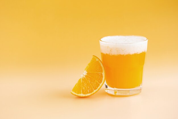 Glas Orangensmoothie frisch zusammengedrückt auf einem orange Hintergrund