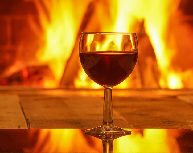 Glas Rotwein gegen gemütlichen Kamin