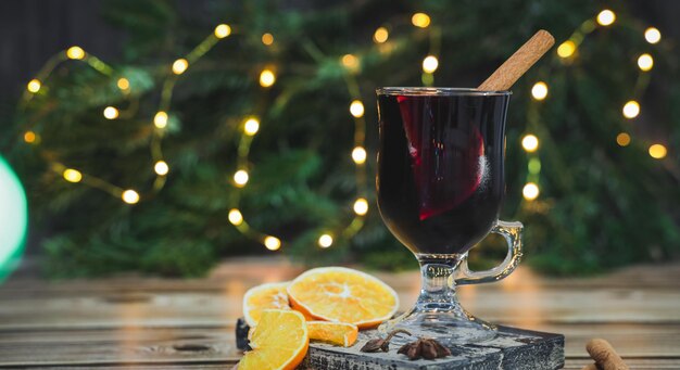 Glas Rotwein Glühwein mit Zimt und Orange auf einem Schneidebrett auf einem Tisch