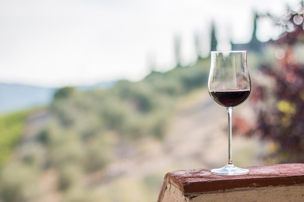 Glas Rotwein in den Weinbergen der Toskana im Hintergrund