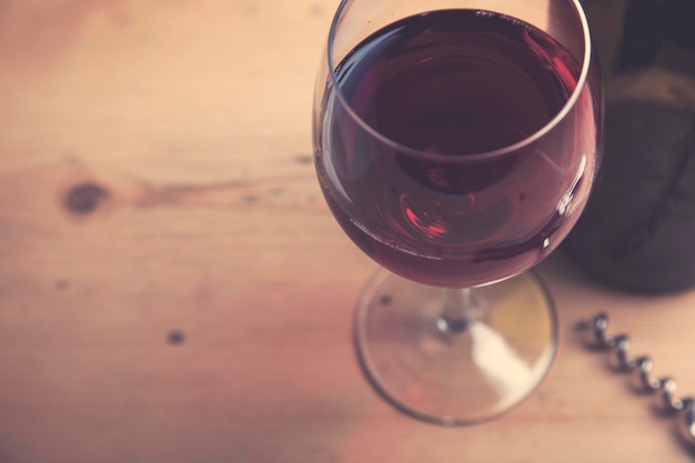 Glas Rotwein mit einer Flasche auf einem hölzernen Hintergrund