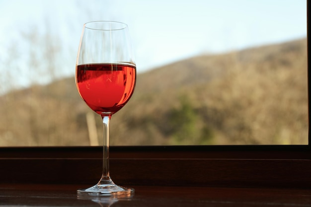 Glas Rotwein steht auf hölzerner Fensterbank