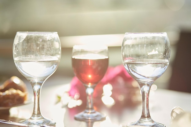 Glas Rotwein und Gläser Wasser auf dem Tisch Dekorationen aus rosafarbenen Bougainvillea-Blumen Kopieren Sie Platz