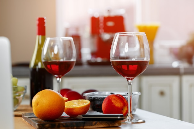 Glas Rotwein und Orangen auf hölzerner Küchentheke