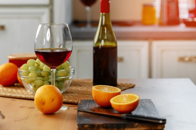 Glas Rotwein und Orangen auf hölzerner Küchentheke