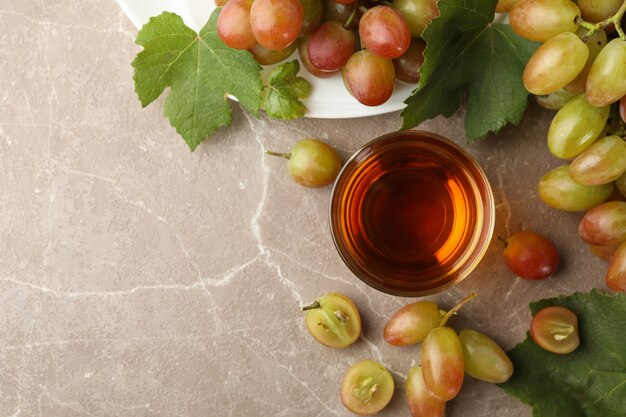 Glas Saft und Teller mit Traube auf grau