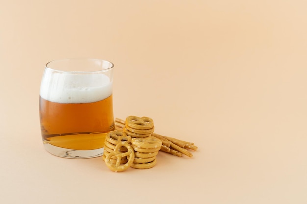 Glas schäumiges erfrischendes Bier mit Brezel auf gelben Hintergrund Kopierplatz
