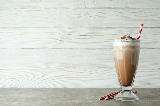 Glas Schokoladenmilchshake und Strohhalme auf grauem Tisch