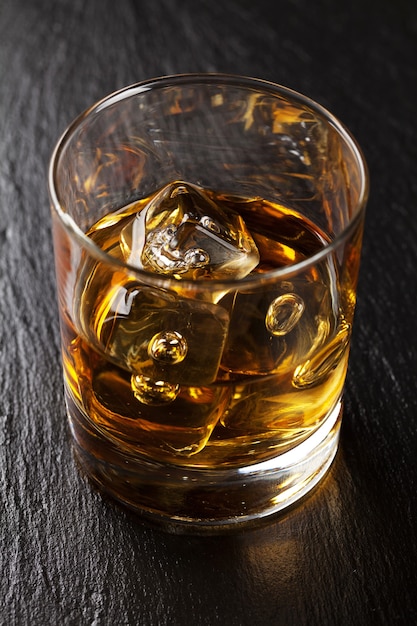 Glas Scotch Whisky mit Eis auf schwarzem Steintisch