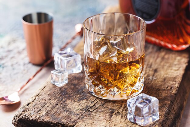 Glas Scotch Whisky mit Eiswürfeln, Flaschen- und Kupferriegelzubehör