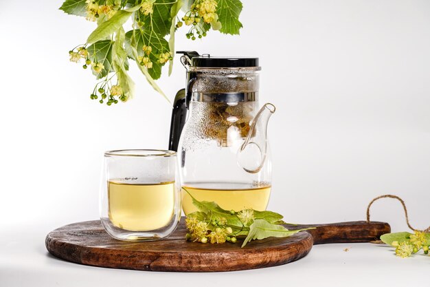 Foto glas teekanne mit gebrautem lindentee und einem transparenten glas auf weißem hintergrund aussicht von der seite