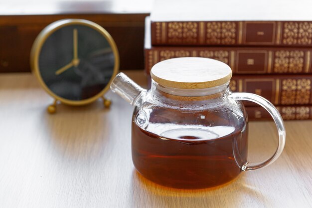 Glas-Teekanne mit schwarzem Tee auf Holztisch