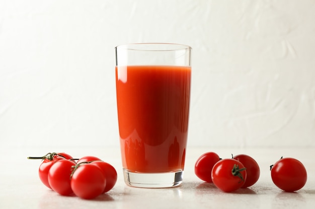 Glas Tomatensaft und Tomaten auf weiß strukturiert