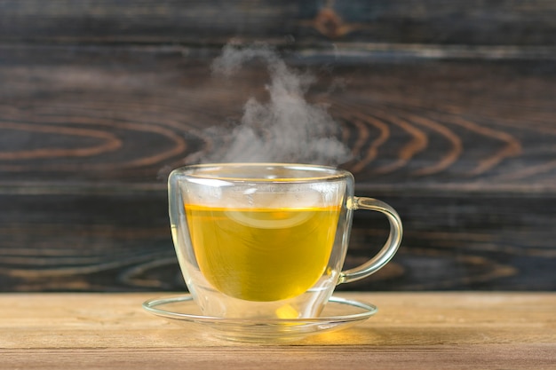 Glas transparente Tasse heißen grünen Tee mit Steamon Holztisch Gesundes Getränk, Antistress Getränkekonzept