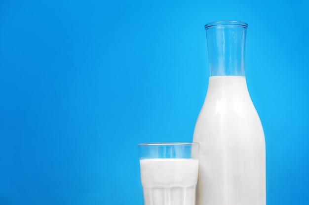 Glas und Flasche mit Milch auf der blauen Hintergrundnahaufnahme