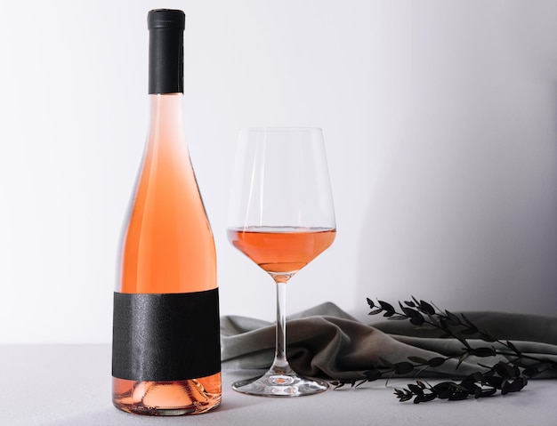 Glas und Flasche Roséwein auf hellem Hintergrund
