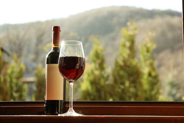 Glas und Flasche Wein stehen auf Holzfensterbank