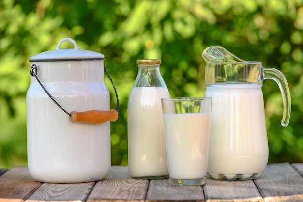 Glas und Krug frische Milch auf Holztisch