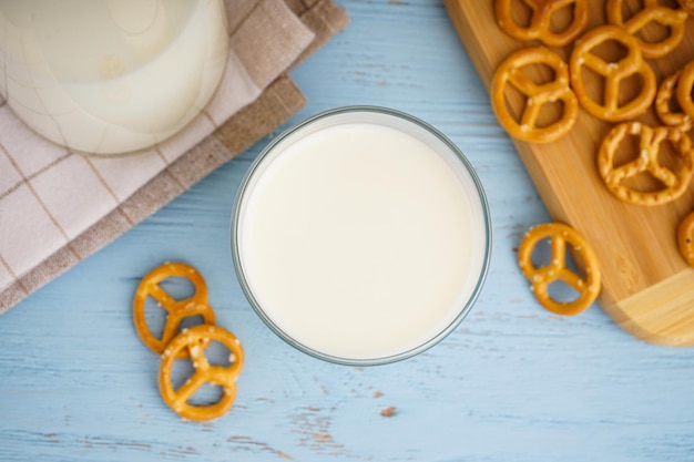 Foto glas und krug mit frischer milch auf holztisch vor farbigem hintergrund, draufsicht