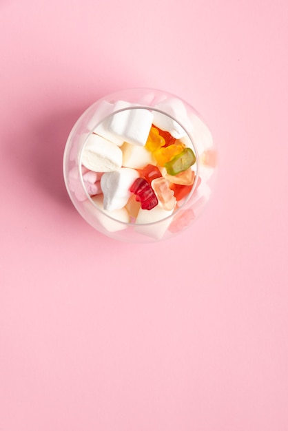 Foto glas voll von zuckerwolken und -gummi betrifft rosa hintergrund