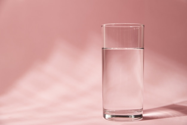 Glas Wasser auf rosa Hintergrund