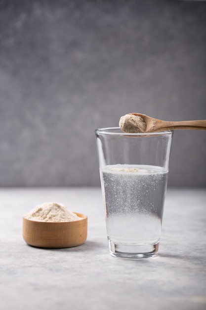 Glas Wasser, Kollagenpulver auf weißem Tisch