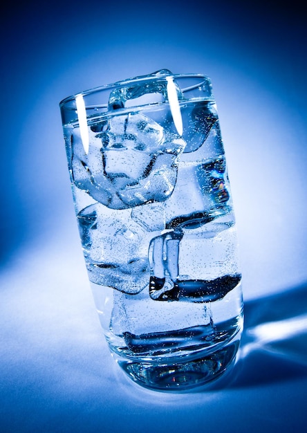 Glas Wasser mit Eis auf dunkelblauem Hintergrund