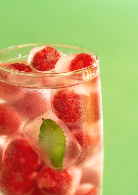 Glas Wasser mit gefrorenen Himbeeren