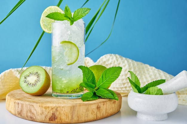 Glas Wasser mit Kiwi-Limette und Minze auf blauem Hintergrund