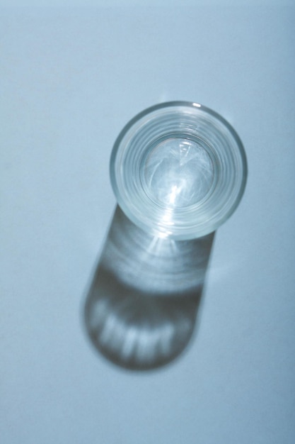 Glas Wasser mit Schatten auf blauem Packgrund