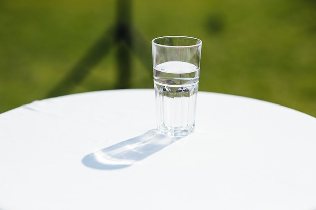 Glas Wasser mit Sonne auf einem weißen Tisch beleuchtet