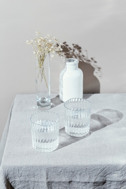 Glas Wasser und Vase mit Blumen