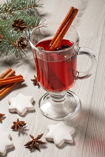 Glas Weihnachtsglühwein mit Gewürzen und Keksen auf Holzbrettern