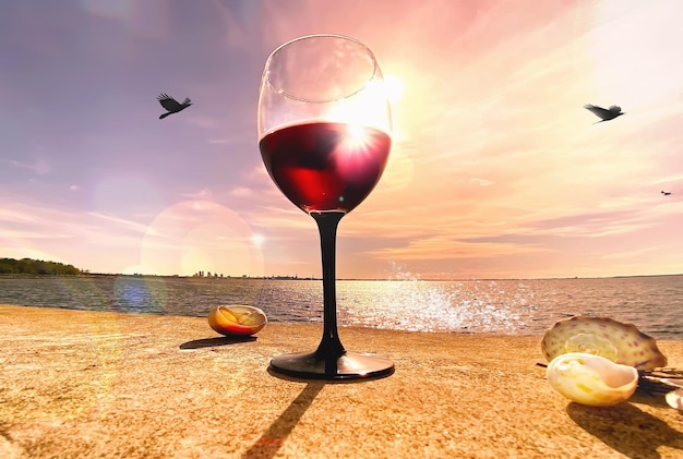 Glas Wein am Strand am Holztisch bei romantischem Sonnenuntergang