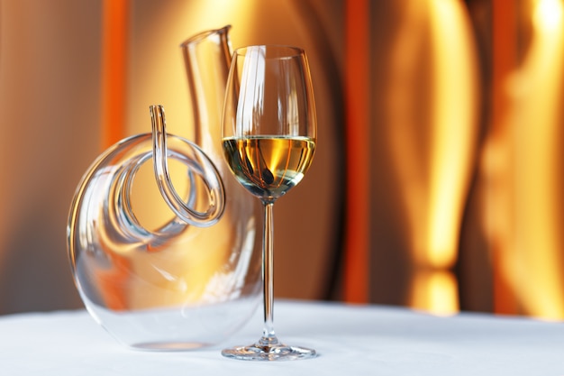 Glas Wein und eine Karaffe auf einem Tisch mit einer weißen Tischdecke.