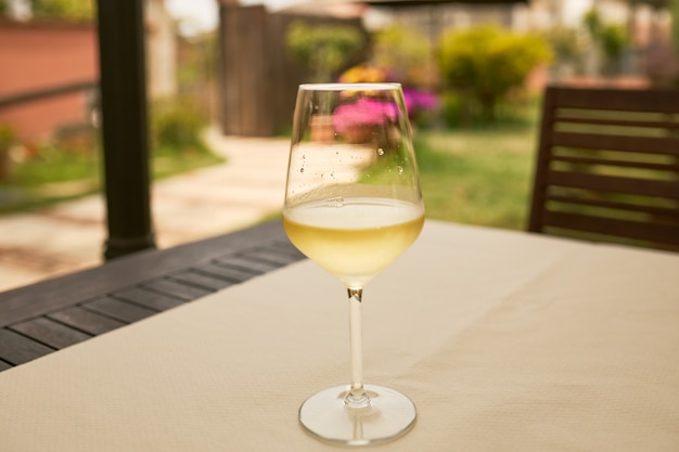 Glas Weißwein auf einem Tisch auf einer Terrasse.