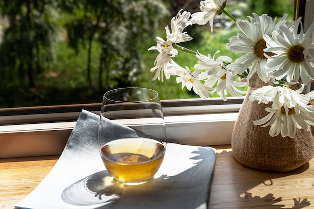 Glas Weißwein und Gartenblumen über grünem Gartenhintergrund.