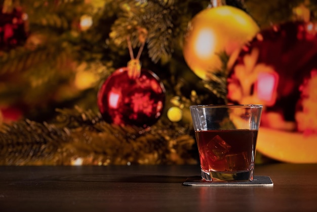Glas Whiskey an der Bar vor dem verschwommenen Bild Weihnachtszimmer mit Baum und festlicher Bokeh-Beleuchtung verschwommener Urlaubs-Hintergrund