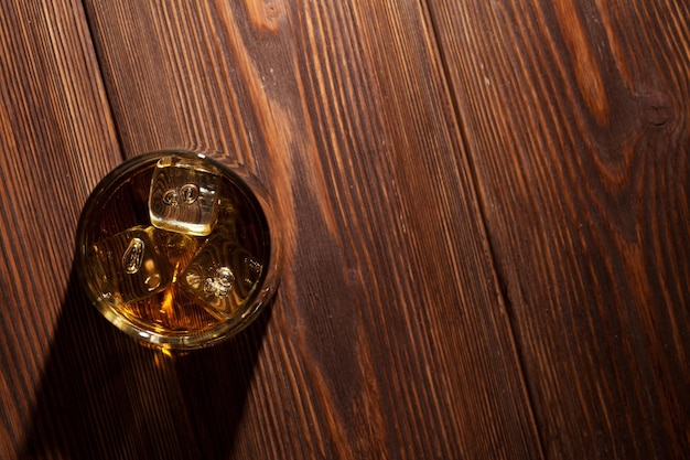 Glas Whiskey mit Eis auf Holz